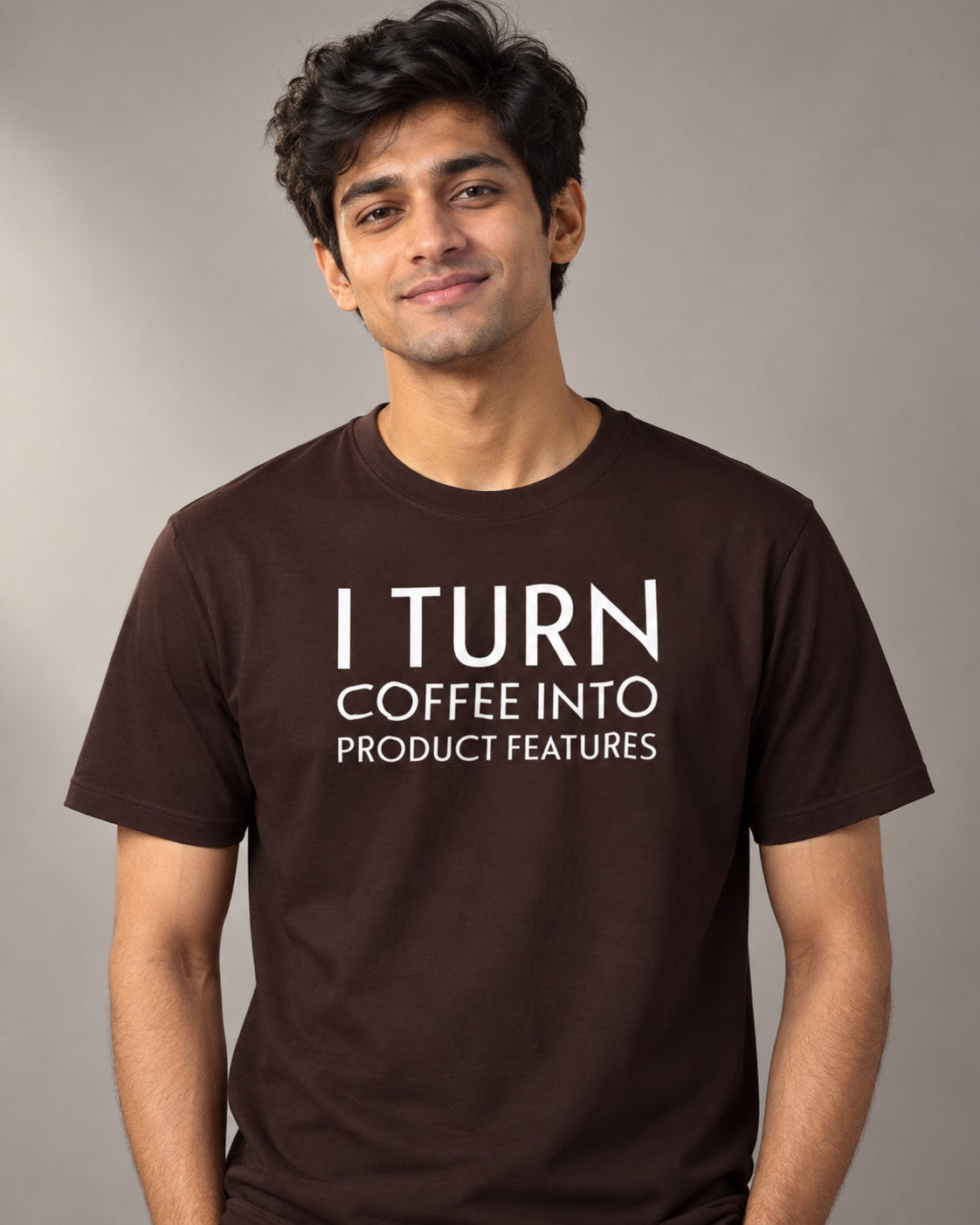 Indian male model wearing the brown I Turn Coffee Into Product Features T-shirt, front view